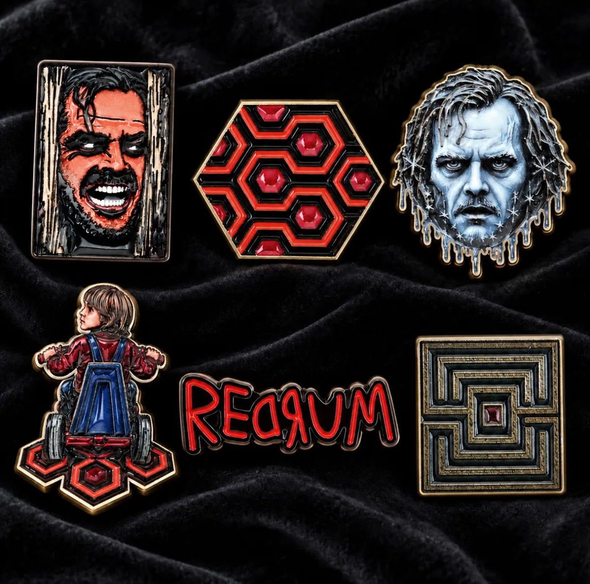 Six The Shining enamel pins displayed on black velvet beneath the heading “The Shining — 6-Piece Enamel Pin Set.”