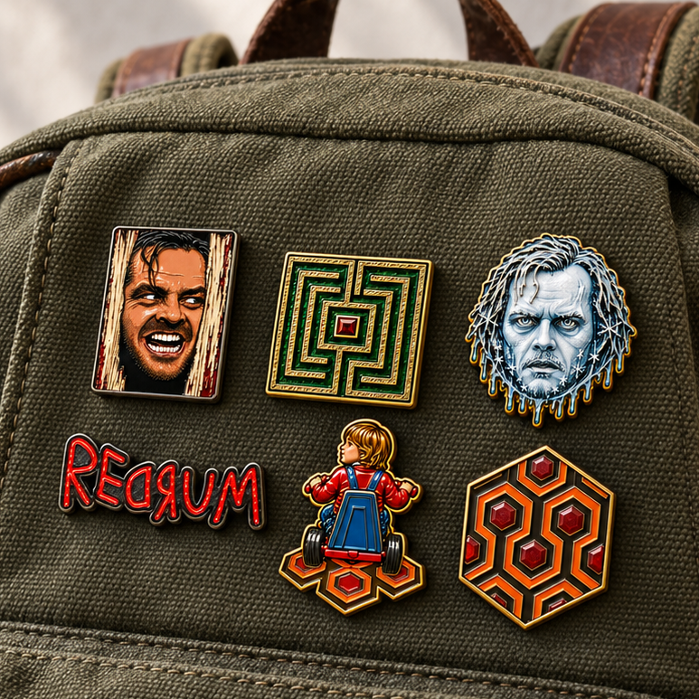 A close-up of an olive green canvas backpack with 6 horror-themed enamel pins attached to the front pocket. The pins are from Movie "The Shining" and they are developed by MCW CARPETBAGS.