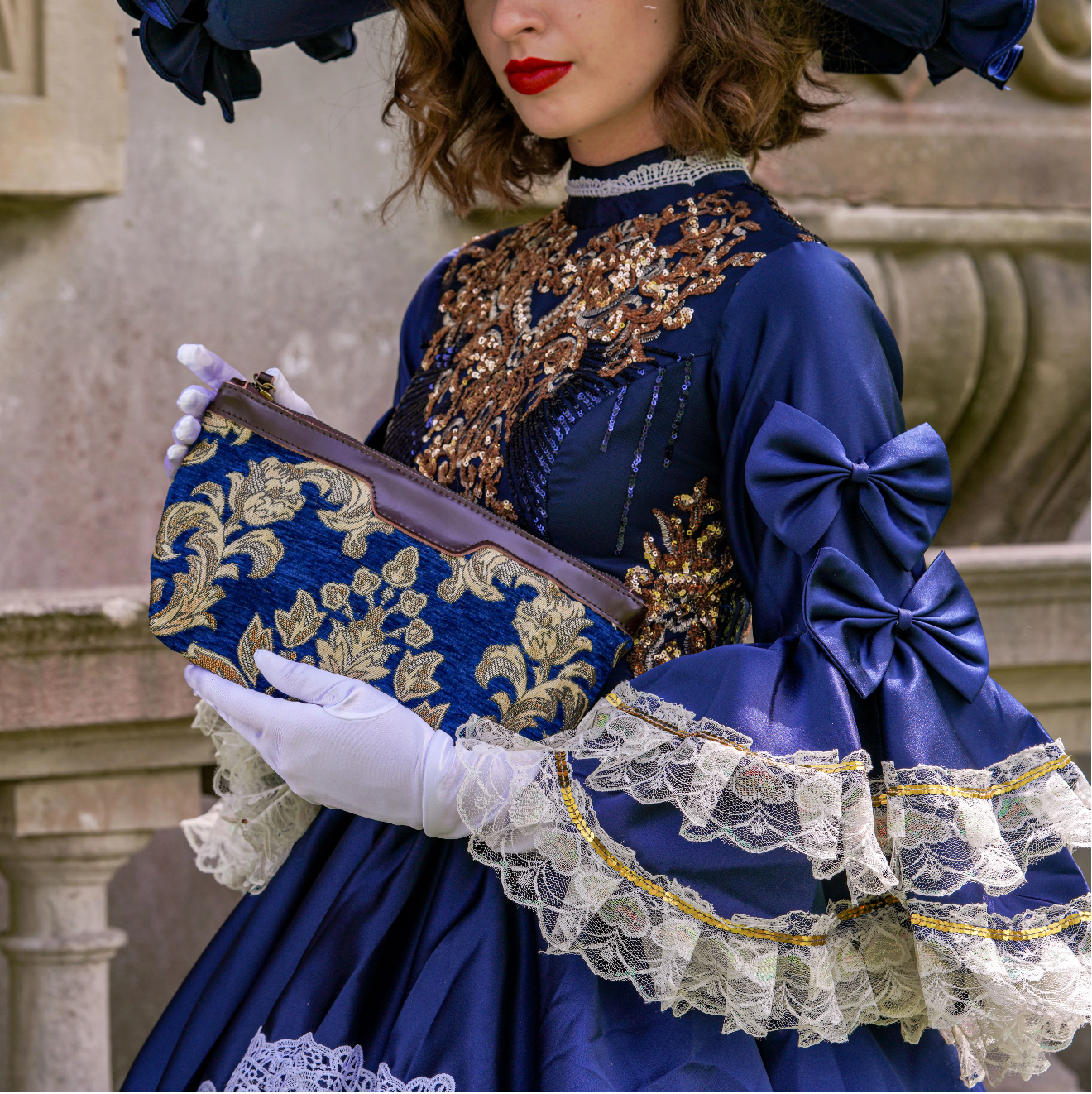 A black-and-white fashion portrait of a woman in vintage clothing holding a floral makeup bag.