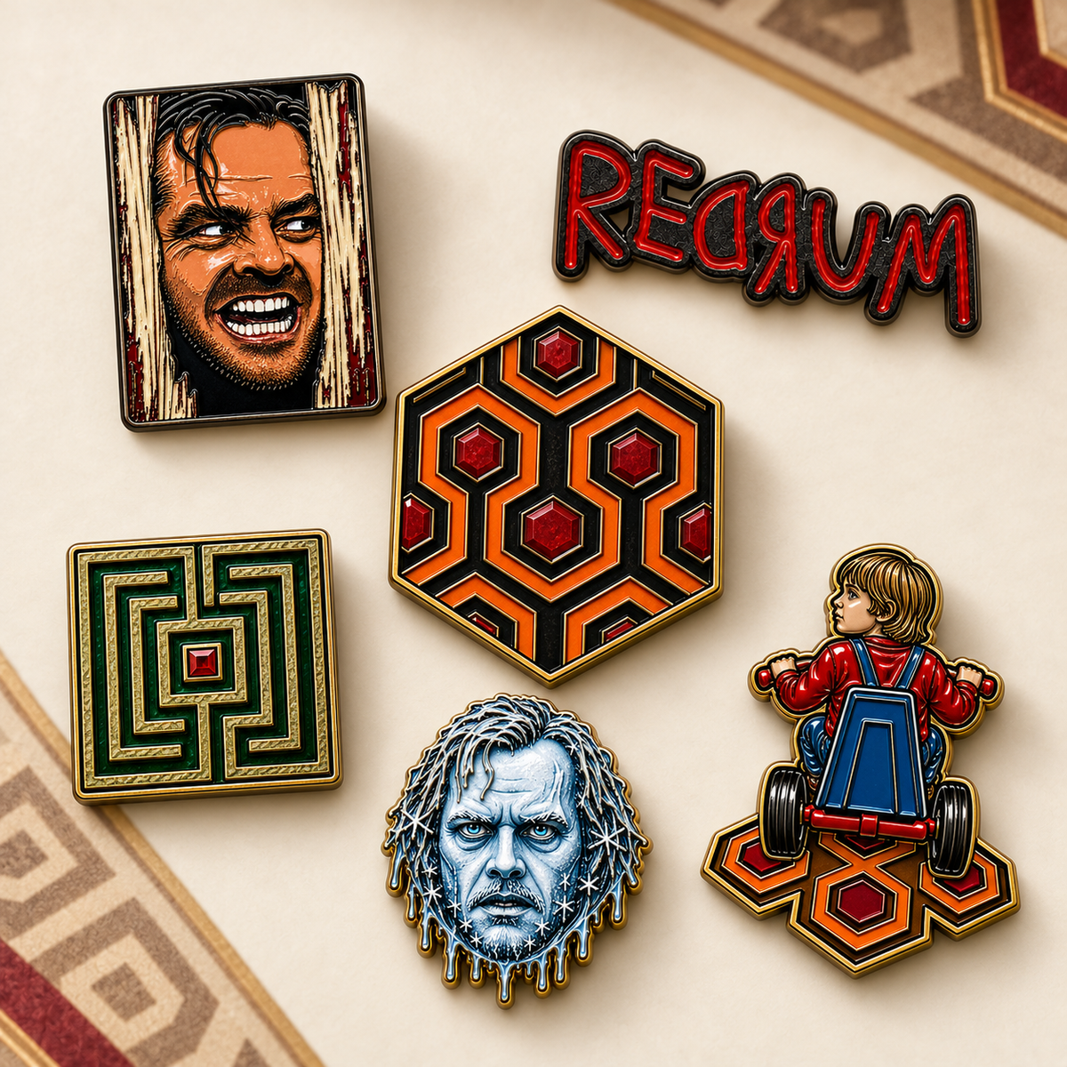 6 horror-themed enamel pins arranged on a beige surface with a patterned rug edge visible. They are from MCW CARPETBAGS Enamel pins of "The Shining".