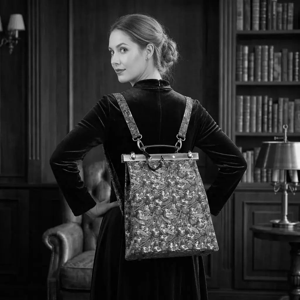 Woman holding a decorative helena backpack in a room with bookshelves and a lamp.