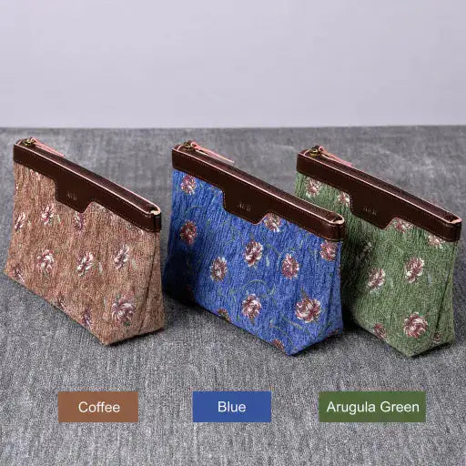 Three floral-patterned carpet makeup bag in Coffee, Blue, and Arugula Green on a gray surface.