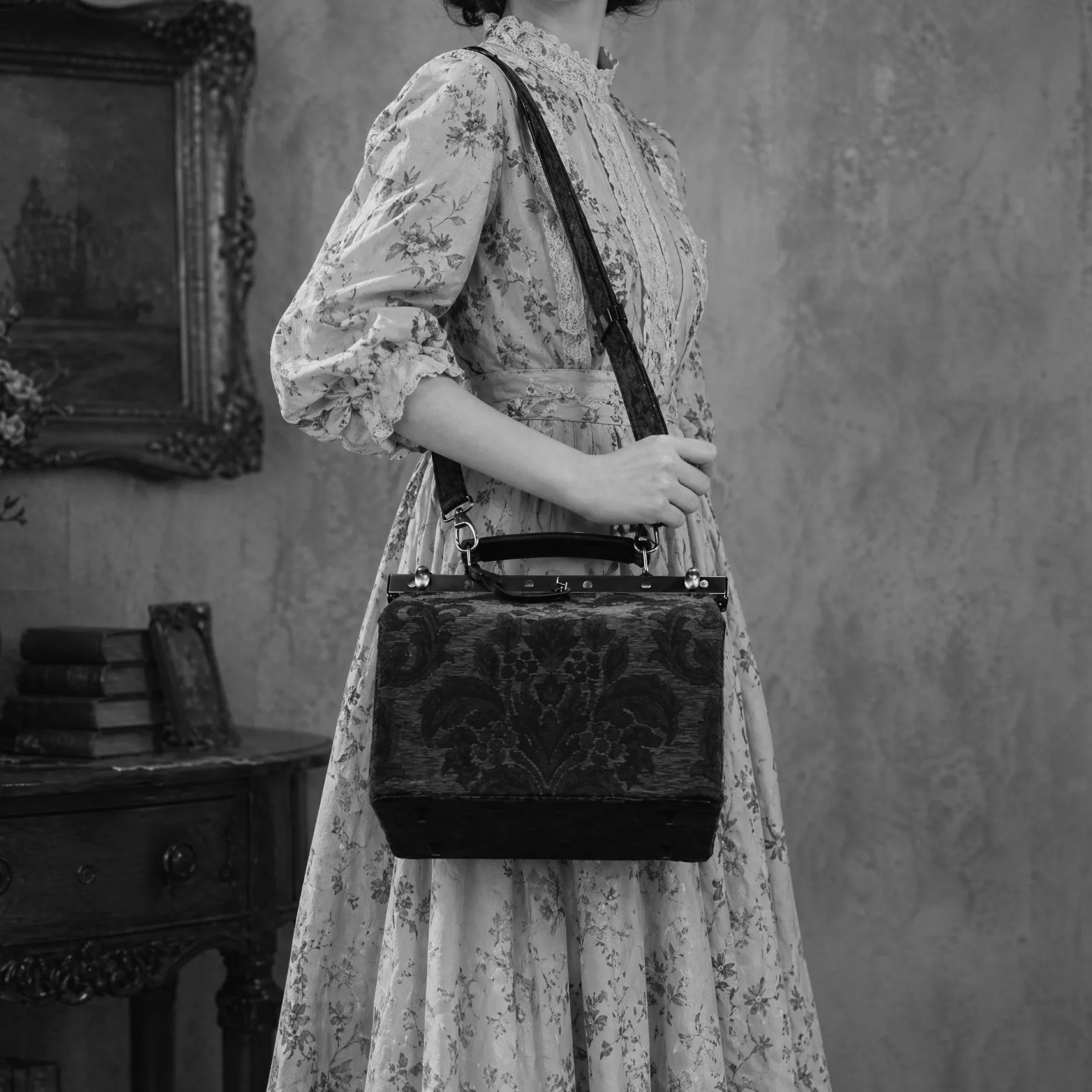 Person holding a vintage-style vivienne purse in a room with a painting on the wall.