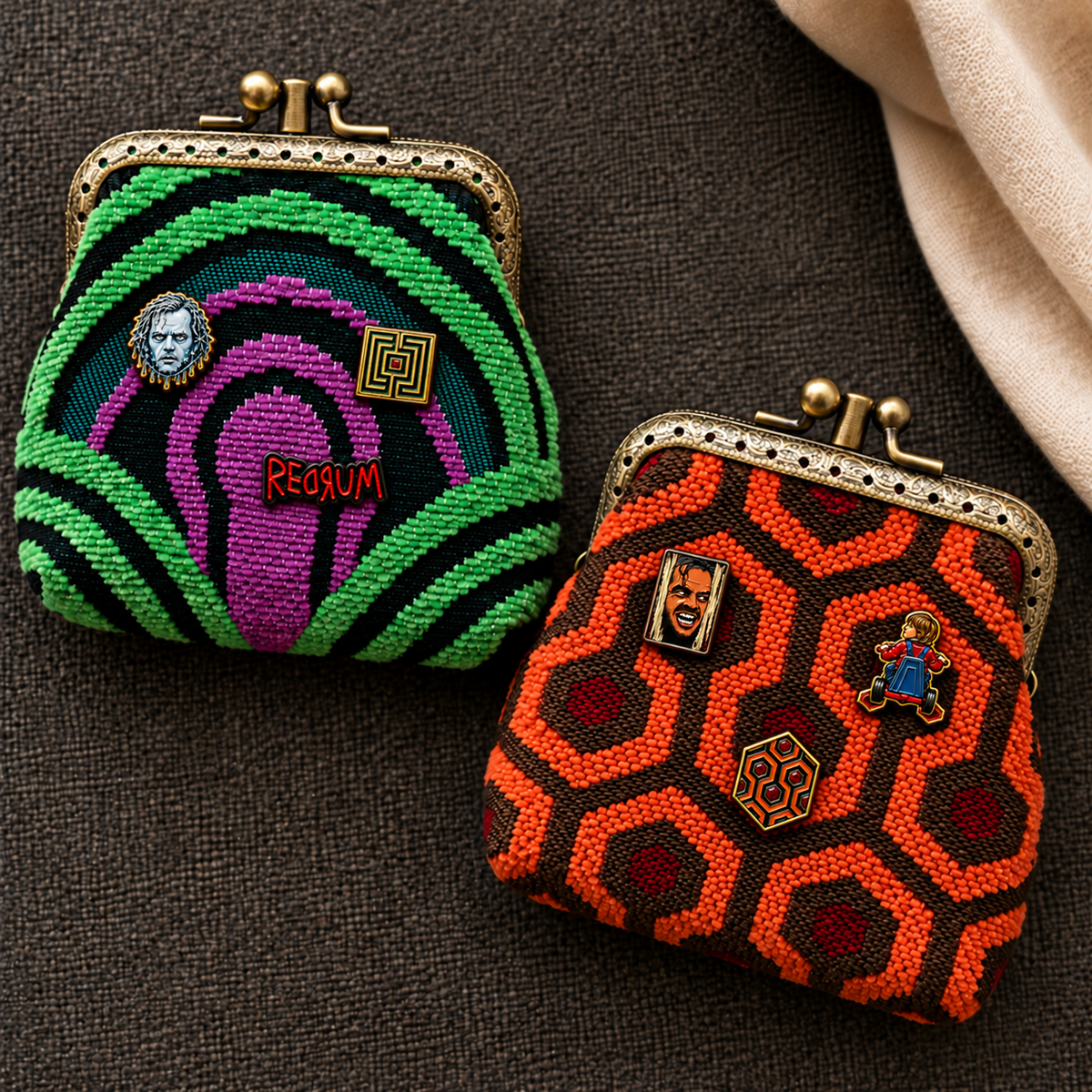 Two small beaded kiss-lock coin purses displayed on a dark textured fabric background. they are from MCW CARPETBAGS,  and both with "The shining" Enamel pin on them.